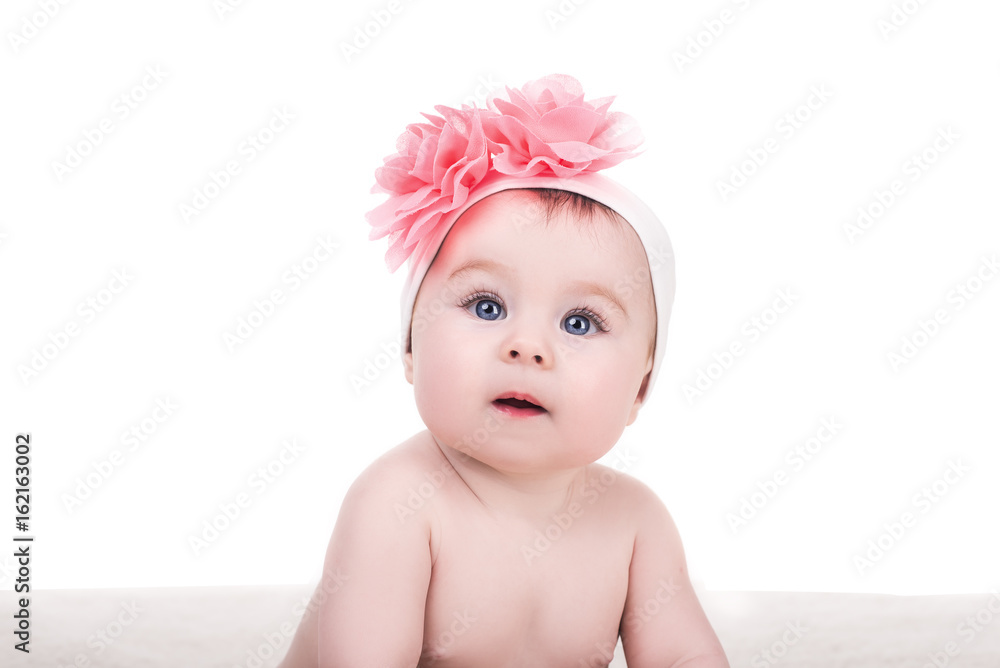 portrait of cute little baby girl with pink bow flower on her head, isolated on white. adorable child with big blue eyes looks into the camera portrait of cute little baby girl with pink bow flower on her head, isolated on white. adorable child with big blue eyes looks into the camera