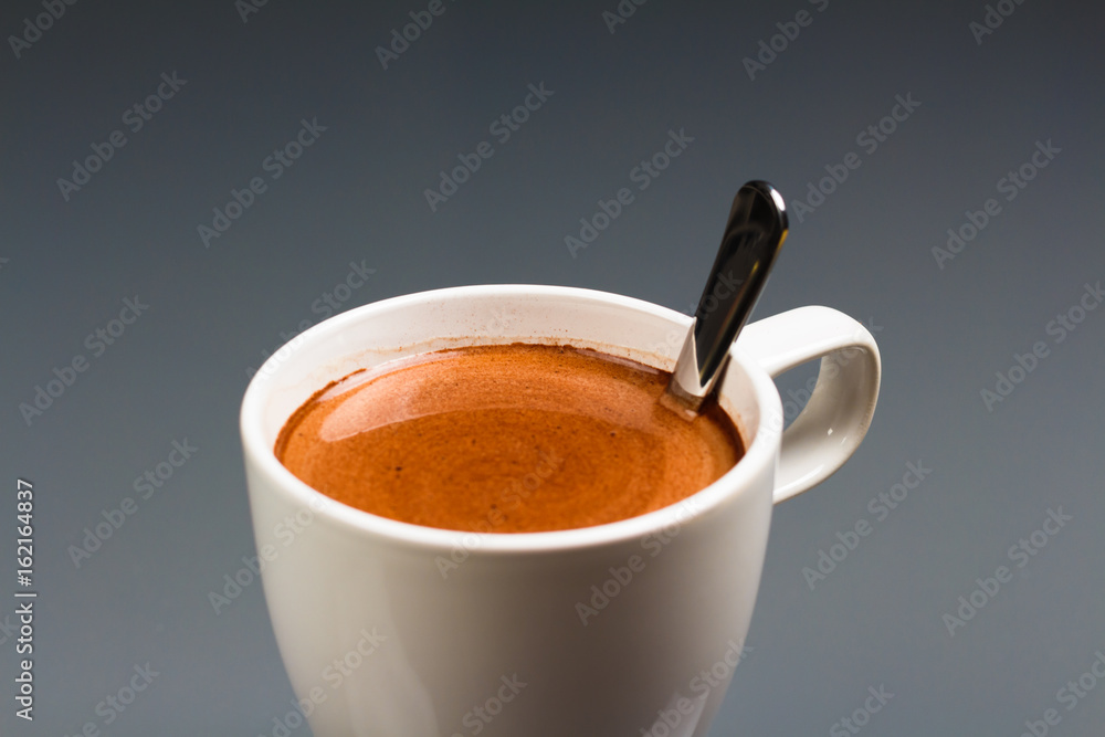 Tasse heiße Schokolade mit Löffel auf grauem Hintergrund, close-up Tasse heiße Schokolade mit Löffel auf grauem Hintergrund, close-up