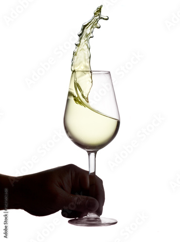 Hnad holding wine glass with splashing white wine isolated on white background, wine tasting concept photo