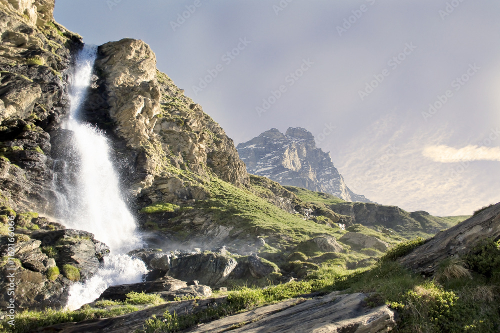 l'acqua della cascata irrompe nella valle con sullo sfondo il cervino l'acqua della cascata irrompe nella valle con sullo sfondo il cervino
