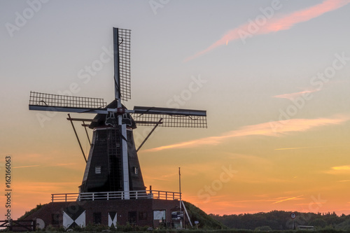 Typical Dutch windmill with a colorful sunset in the background