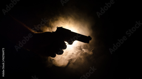 Canvas Print Male hand holding gun on black background with smoke ( yellow orange red white )