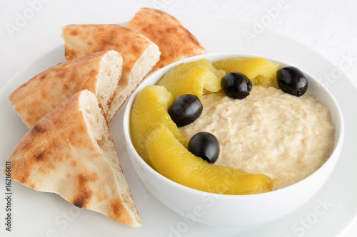 salad of baked aubergine, yogurt, and garlic dressed with lemon juice and decoreted with pepper and olives served with flatbread photo