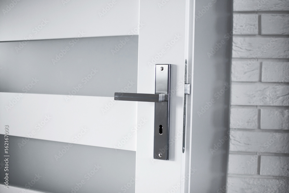 Fototapeta premium White door with metal shiny handle in modern house.