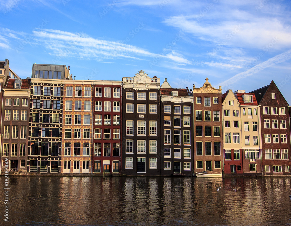 Beautiful traditional old buildings at day with bright blue sky in Amsterdam, the Netherlands