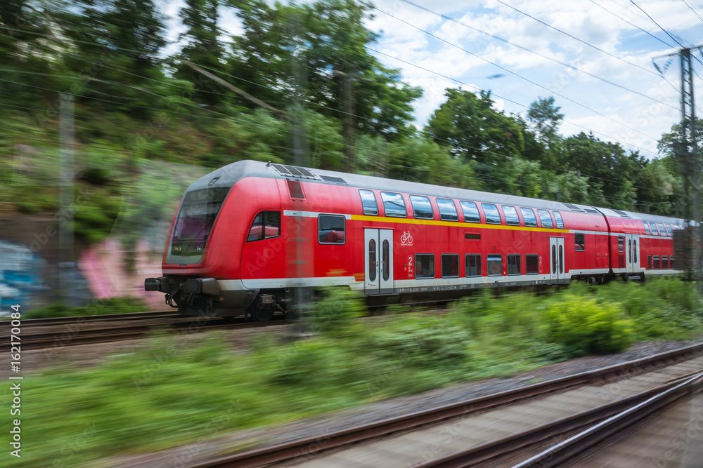 Fototapeta premium Red European Train Public Transport Motion Blur through Outdoors Area Traveling