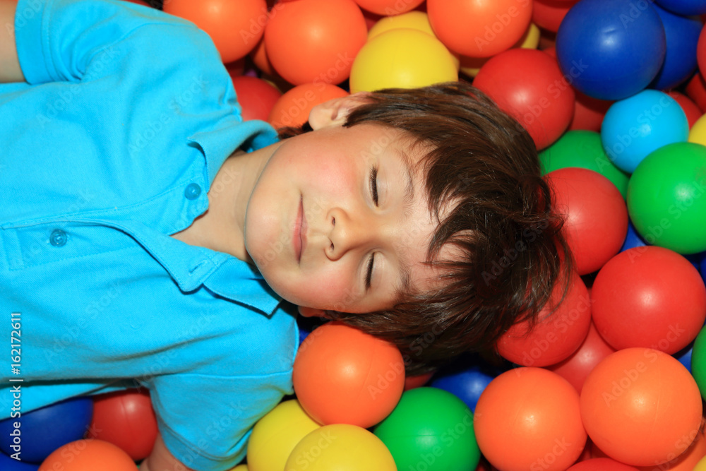 niño durmiendo feliz en piscina bolas de colores Stock Photo | Adobe Stock
