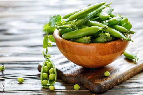 Fresh green peas in a wooden bowl.
