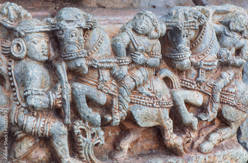 Warriors and horseriders on stone sculptures of decoration inside the Hindu temple. Walls with artworks and designed patterns of 12th centur Hoysaleshwara temple in Halebidu, India. photo