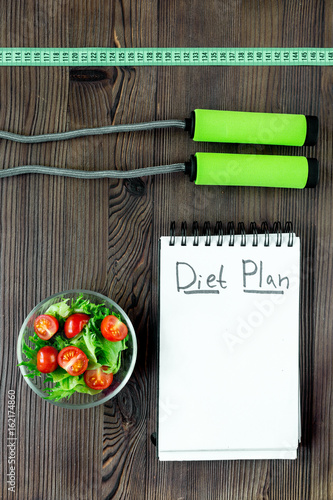 Tasty food for slimming. Notebook for diet plan, salad and fruits on wooden table top view mock up