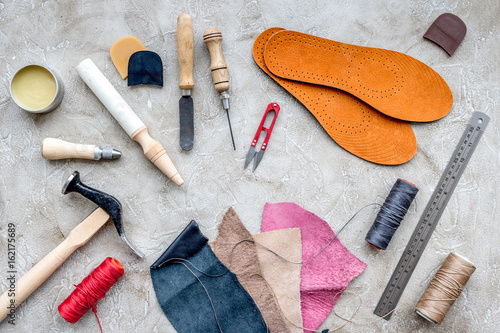 Set of cobbler tools on grey stone desk background top view