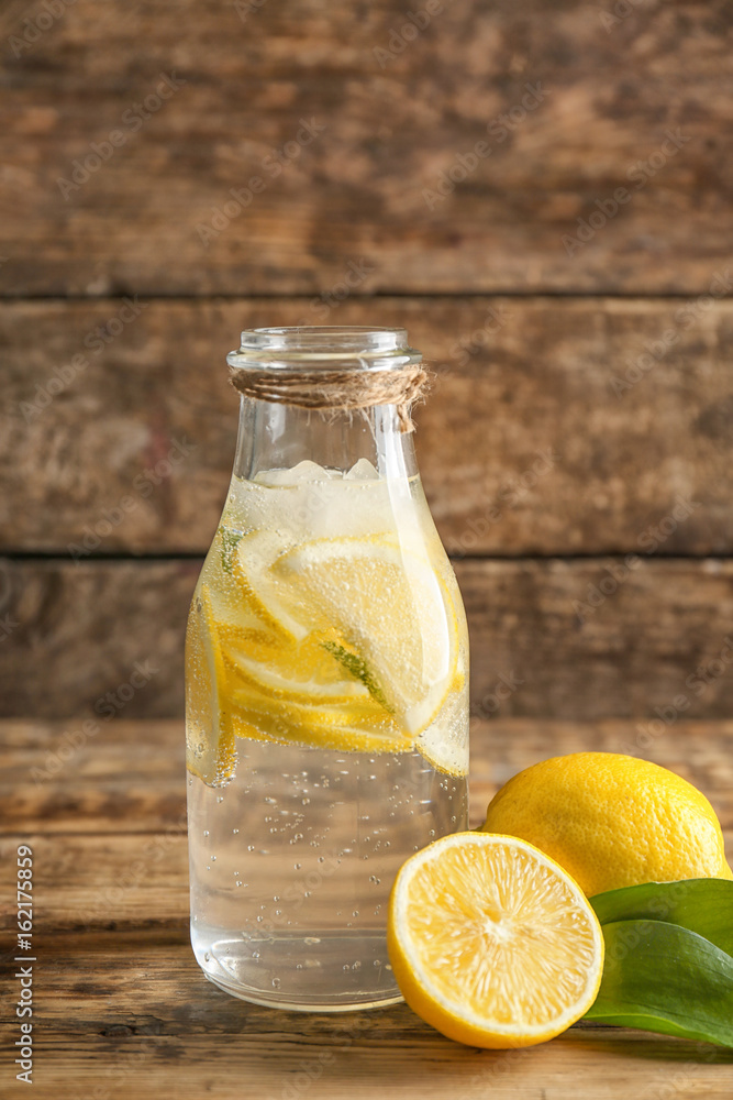 Bottle with cold lemon water on wooden table Bottle with cold lemon water on wooden table