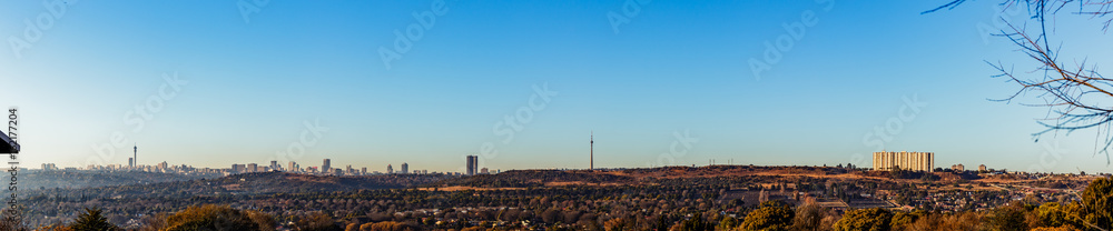 Naklejka premium Wide Panorama view of Johannesburg City Skyline on a winter morning with mist low and clear skies