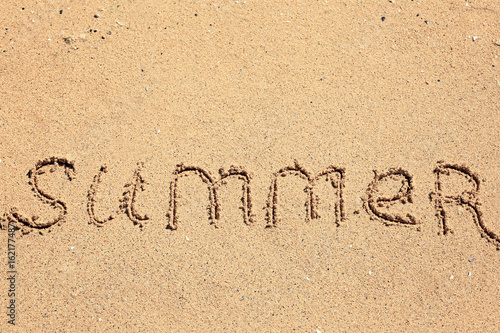 Word SUMMER written on beach sand. Vacation concept