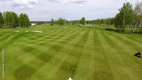 Aerial view Golf course. Golfers walking down the fairway on a course with golf bag and trolley photo