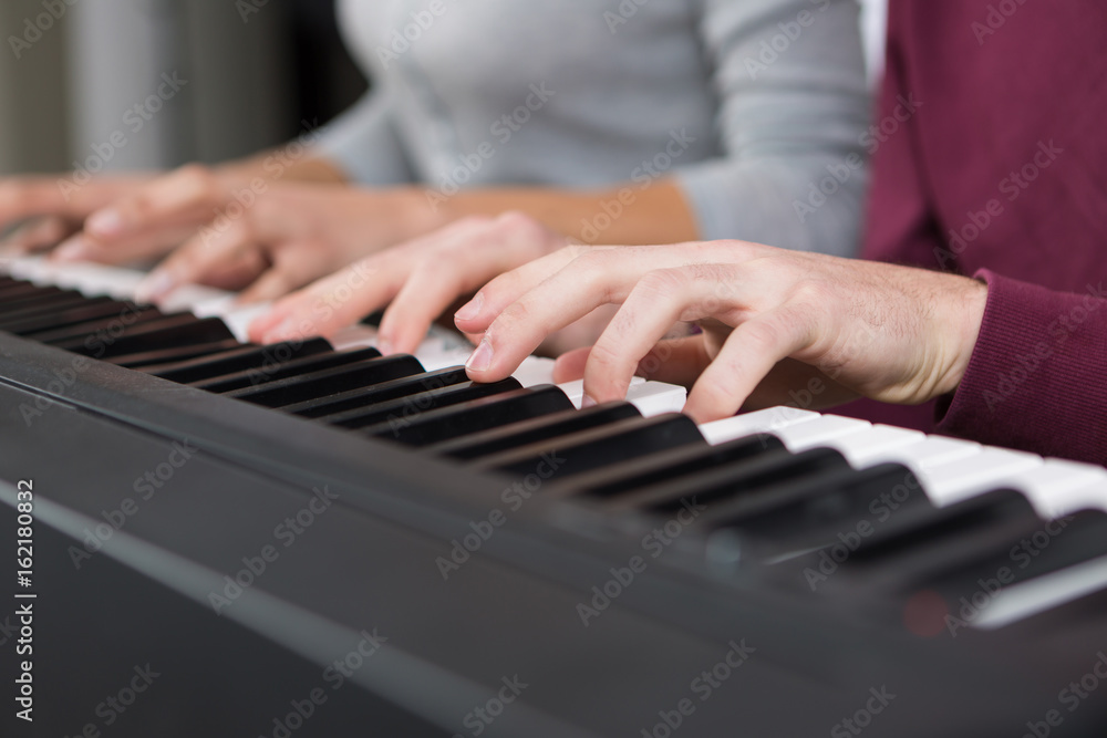 Fototapeta premium 4 hands playing piano close up