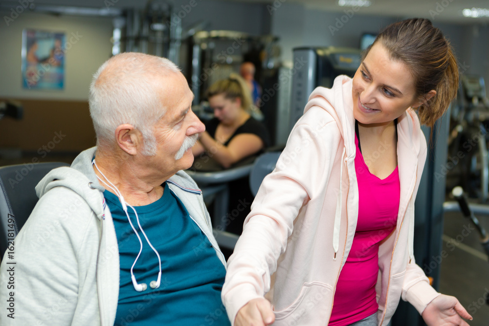 Obraz premium senior man and trainer exercising in gym