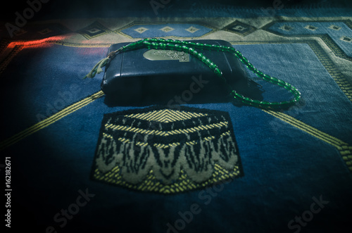 Holy Quran with beads on a prayer mat, Muslim Tasbih is a string of prayer beads which is traditionally used by Muslims along with the Quran. Ramadan holidays concept photo