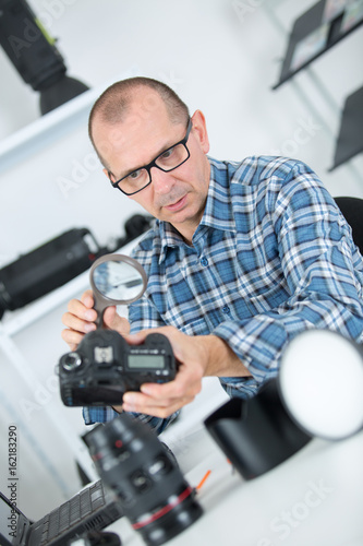 technician engineer checking dslr sensor with magnifying glass