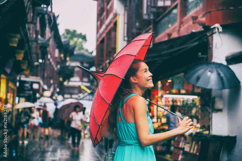 Naklejka premium Ludzie styl życia parasol podróży Asian kobieta zakupy w chinatown market street. Deszczowy dzień dziewczyna turystycznych pod czerwonym parasolem orientalne w tylnych zaułkach w Szanghaju w Chinach.