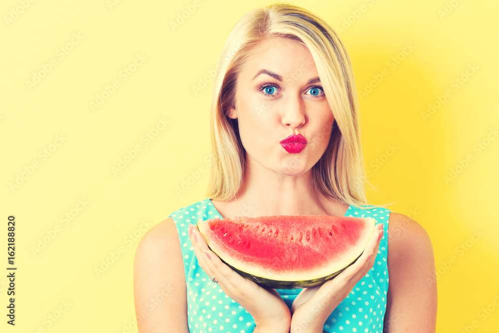 Happy young woman holding watermelon on a yellow background Happy young woman holding watermelon on a yellow background