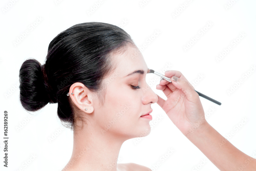 Stylist applying apply makeup on a eyebrows to the beautiful woman Stylist applying apply makeup on a eyebrows to the beautiful woman