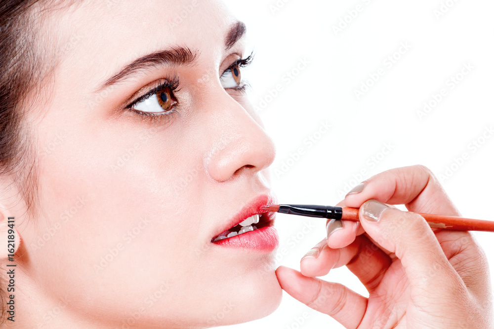 Stylist applying red lip gloss to the beautiful woman