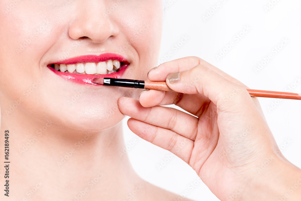 Stylist applying red lip gloss to the beautiful Woman Stylist applying red lip gloss to the beautiful Woman