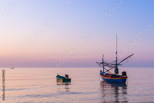 Sunrise at the Sea with fisher boats and cloudy sky