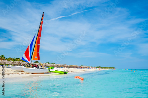 Photography The tropical beach of Varadero in Cuba with a colorful sailboat