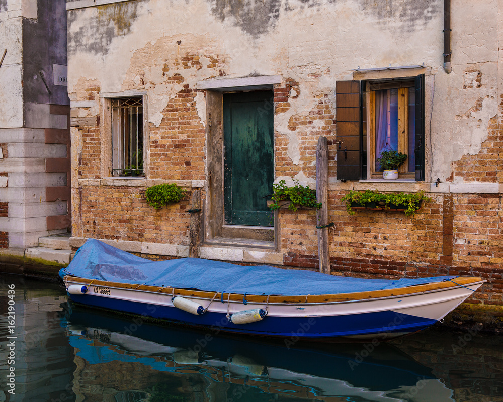 Boat in front of old house on canal in Venice