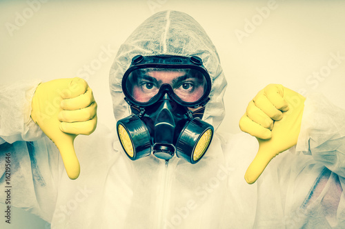 Man in coveralls with gas mask is showing negative gesture