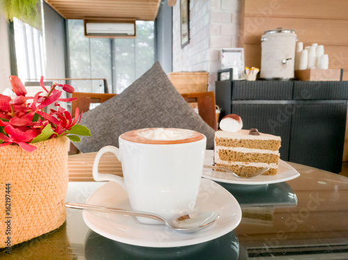 A hot mocha coffee with red orchid and mocha cake on the cozy coffee table