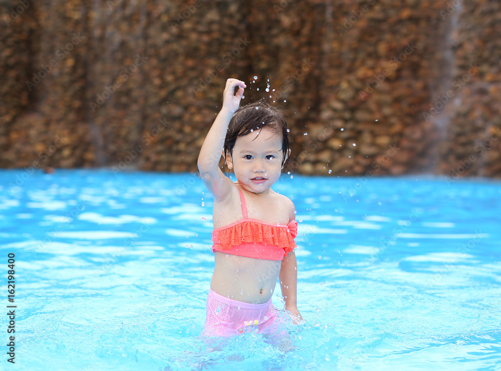 Naklejka premium Pretty little girl playing in swimming pool outdoors.