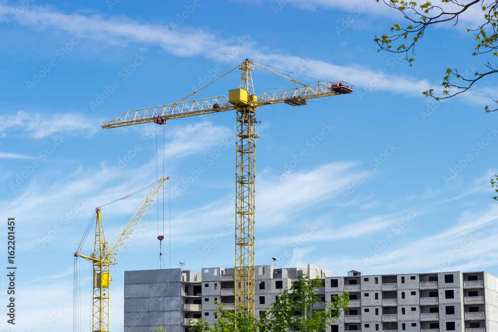 Two tower cranes against of multi-story residential building construction Two tower cranes against of multi-story residential building construction