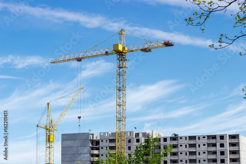 Two tower cranes against of multi-story residential building construction