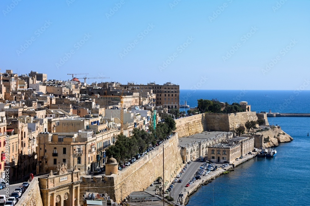 Elevated view of city buildings on the East side of the grand harbour with Victoria Gate in the foreground, Valletta, Malta.