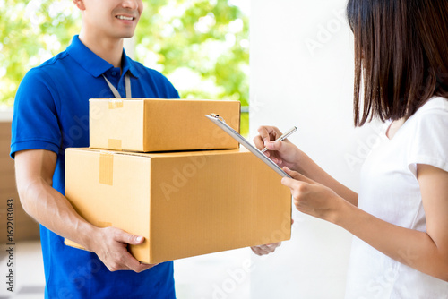 Woman signing document, receiving parcel box from delivery man