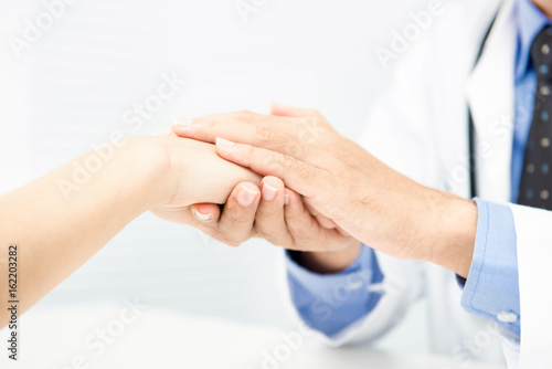 Doctor holding patient hand with care, giving comfort