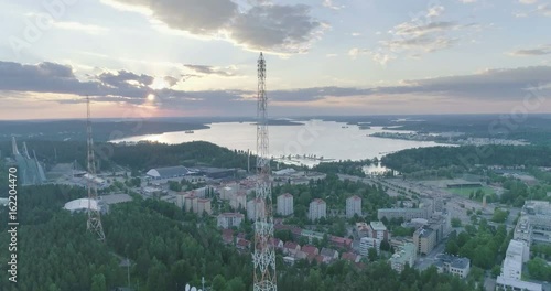 Evening aerial view of ski jumping hills, radio towers and lake in Lahti, Finland, forward movement