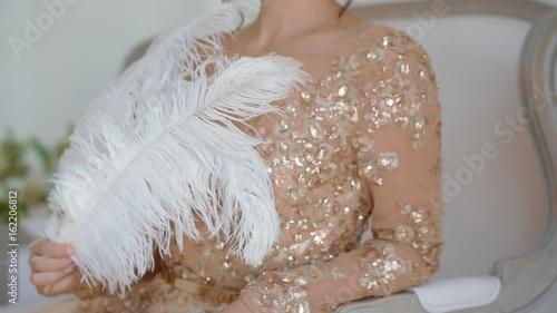 Gergeous woman in golden dress with ostrich feathers posing in studio. photo