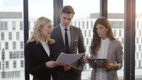 Business meeting of three people against office Window. Shot with a Red dragon in 4K down convert to HD