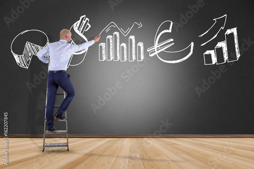 Businessman in front of a wall writing on hand drawn business interface - business concept photo