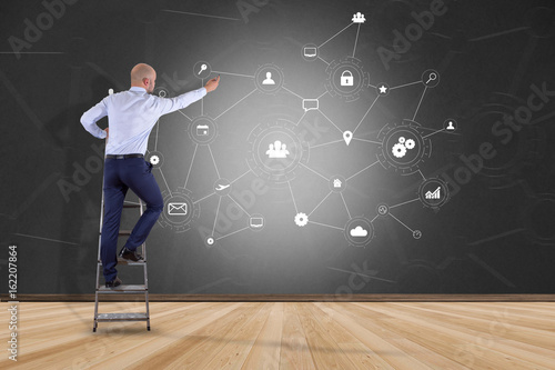 Businessman in front of a wall with a business network connection displayed on a futuristic interface with technology icon - Worldwide business concept