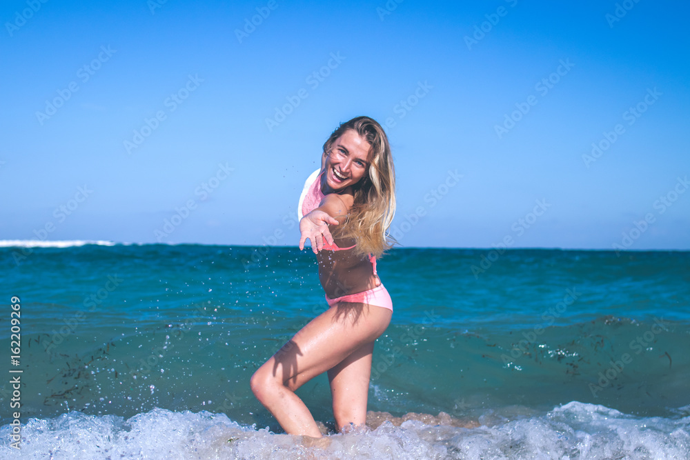 Beautiful young woman in bikini on the beach splashing water. Tropical island Bali, Indonesia. Beautiful young woman in bikini on the beach splashing water. Tropical island Bali, Indonesia.