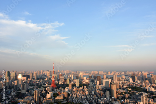 青空と雲と太陽の光を浴びるビル、日本の東京都市景観（港区や江東区方面などを望む） © Ryuji