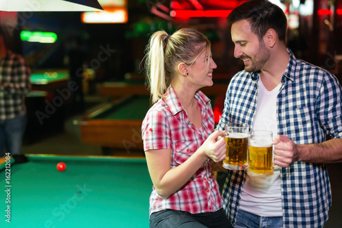 Happy couple drinking beer and playing snooker