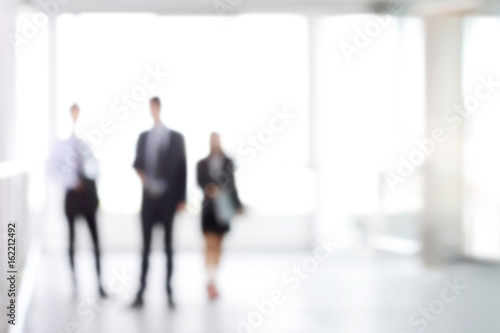 Blurred business people standing in white office building hall