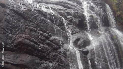 Rushing waterfall in the mountains with tropical forest. Beautiful nature background. Close up