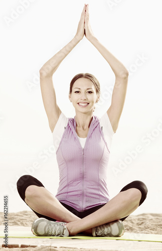 Young smiling woman practise yoga cross-legged